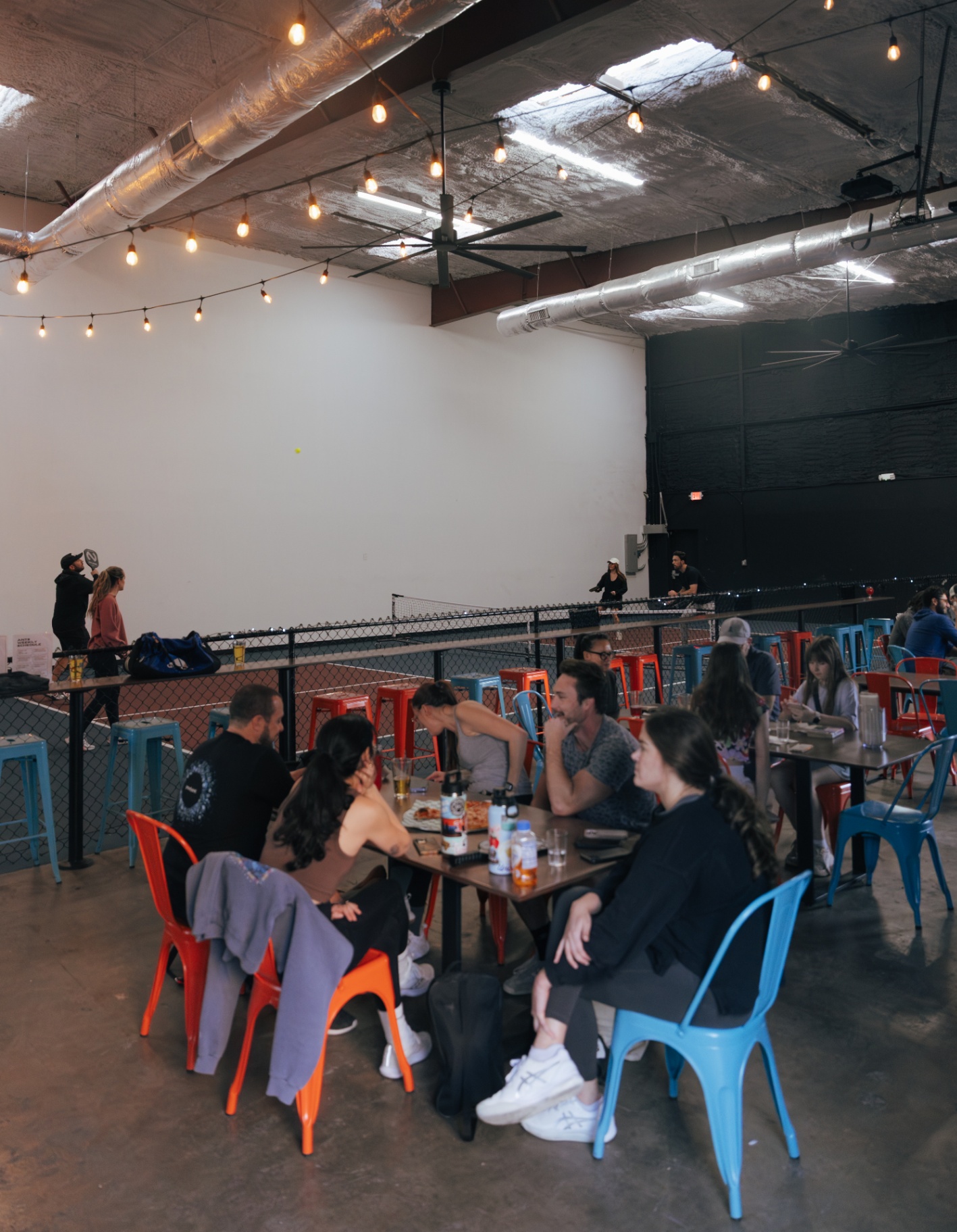Colorful metal chairs and picnic tables lined up courtside inside the warehouse